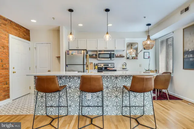 a kitchen with stainless steel appliances granite countertop a stove a refrigerator a dining table and chairs with wooden floor