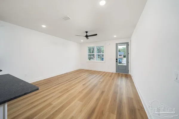 an empty room with wooden floor and windows
