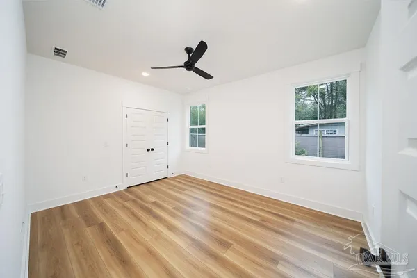 a view of empty room with wooden floor and fan
