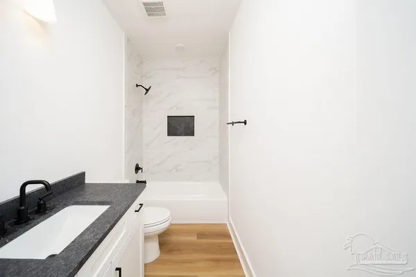 a bathroom with a granite countertop sink a toilet and shower