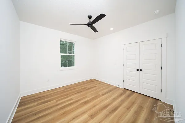 a view of empty room with wooden floor and ceiling fan