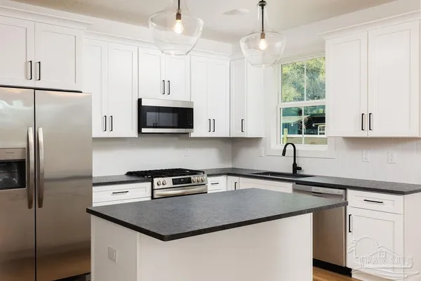 a kitchen with stainless steel appliances granite countertop a sink a stove a refrigerator a microwave a sink and cabinets