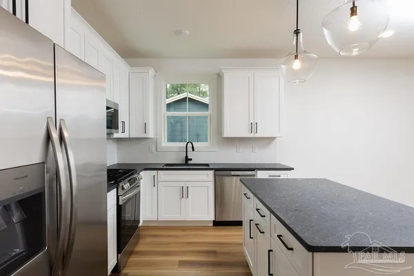 a kitchen with stainless steel appliances granite countertop a sink a stove and a refrigerator