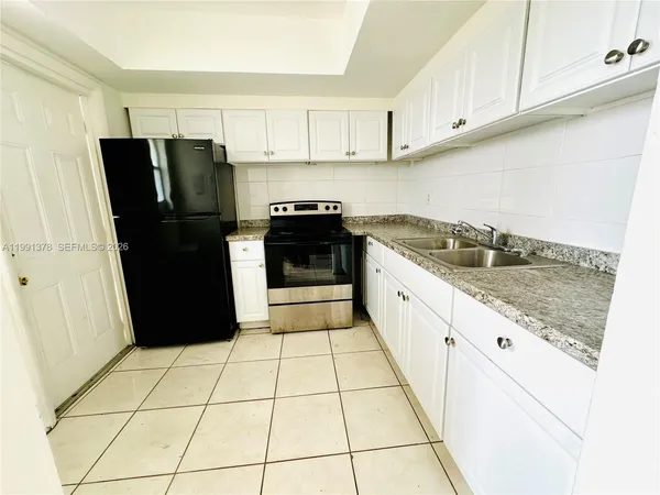 a kitchen with a sink a refrigerator and cabinets