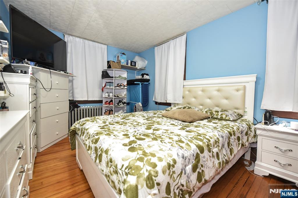 423 North 8th Street Fairview, NJ 07022 - Photo 28 of 30 a bed sitting in a bedroom next to a window with a flat tv screen and dresser