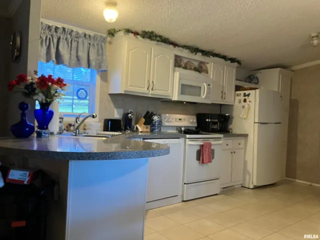 a kitchen with stainless steel appliances granite countertop a sink a stove a dining table and chairs with cabinets