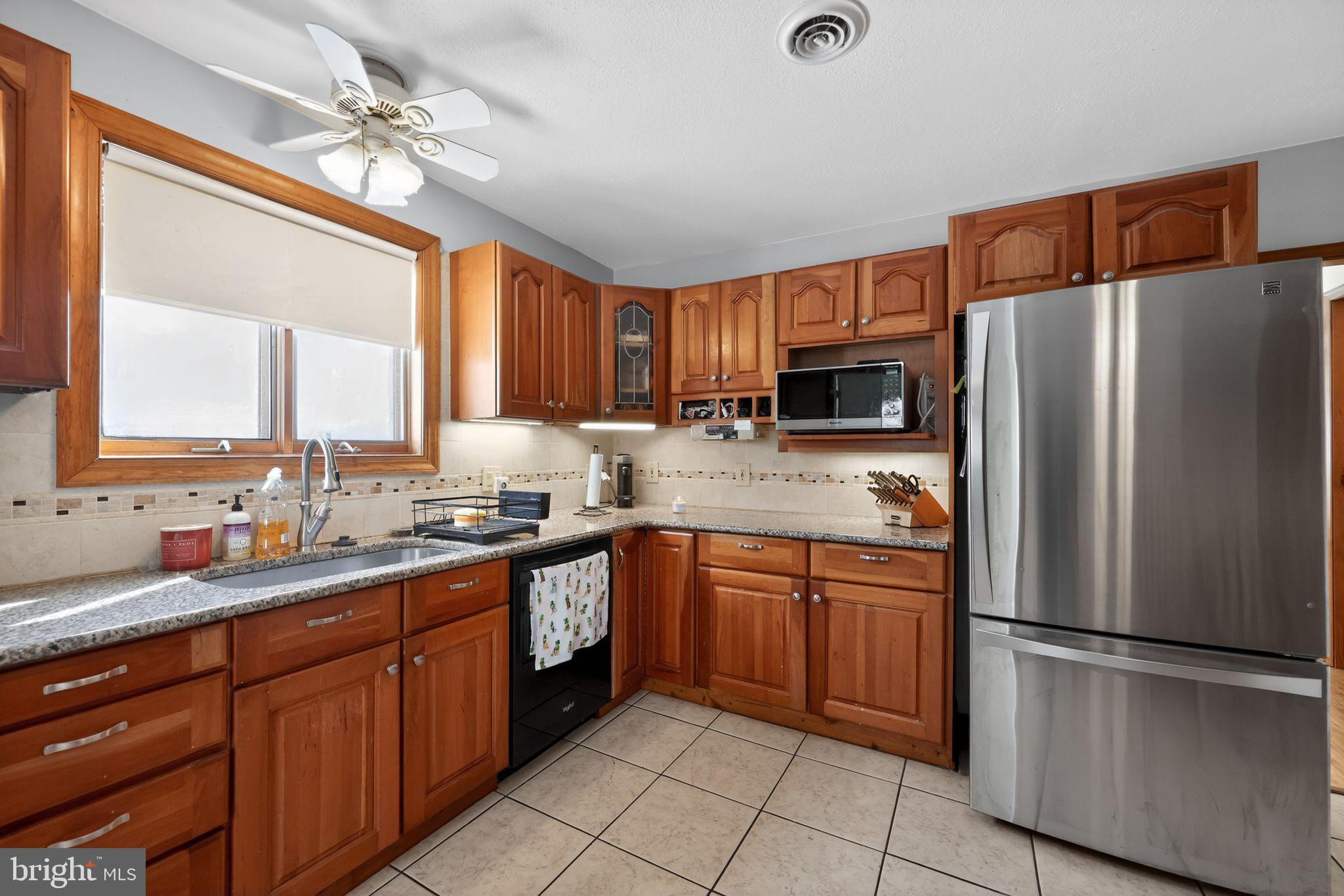 3206 Manor Road Huntingdon Valley, PA 19006 - Photo 13 of 37 a kitchen with stainless steel appliances granite countertop a refrigerator a sink dishwasher a stove with wooden cabinets and floor