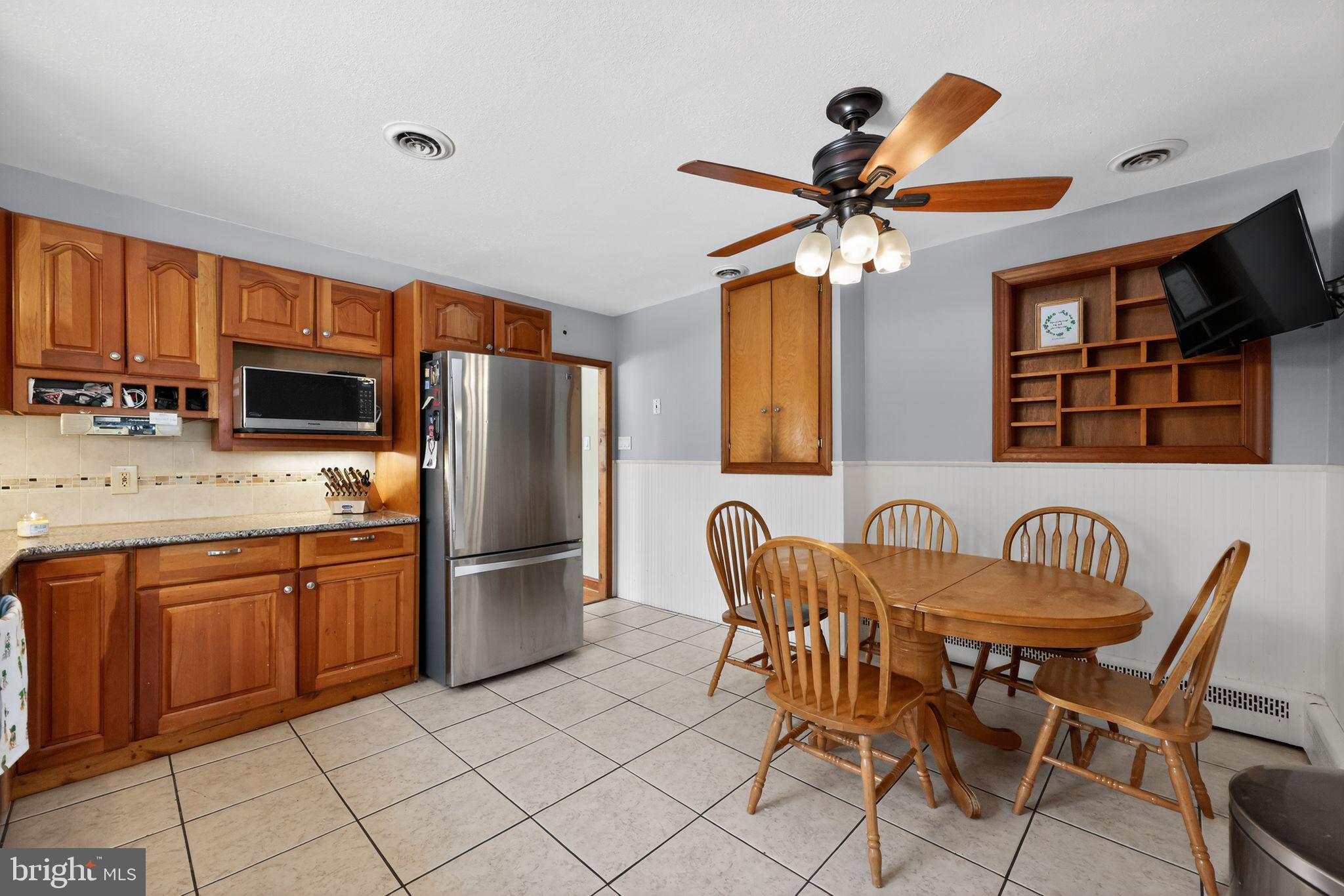 3206 Manor Road Huntingdon Valley, PA 19006 - Photo 14 of 37 a kitchen with stainless steel appliances granite countertop a stove refrigerator a microwave oven with a dining table and chairs