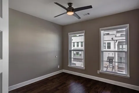 a view of an empty room with a window and wooden floor