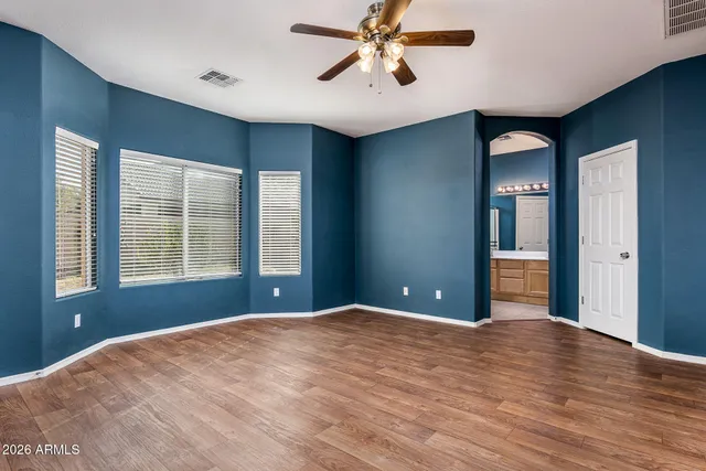 a view of empty room with wooden floor and fan