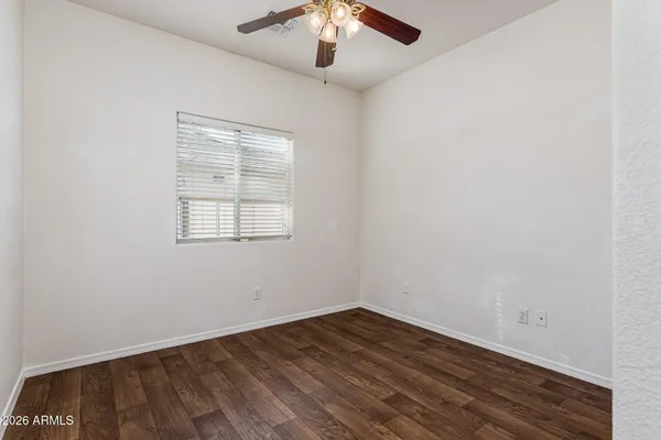 an empty room with wooden floor chandelier fan and windows