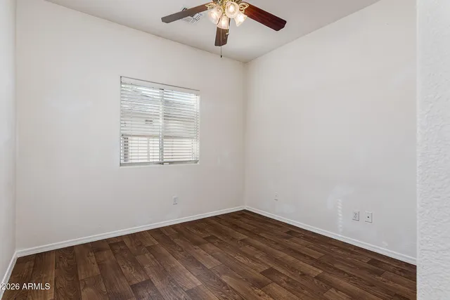 an empty room with wooden floor chandelier fan and windows
