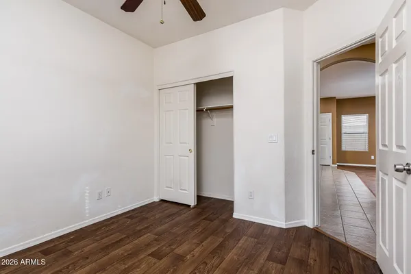 an empty room with wooden floor and a ceiling fan
