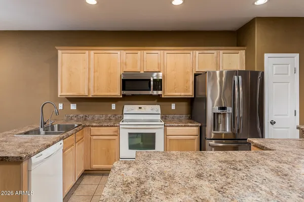 a kitchen with stainless steel appliances granite countertop a stove a sink and a refrigerator with wooden floor