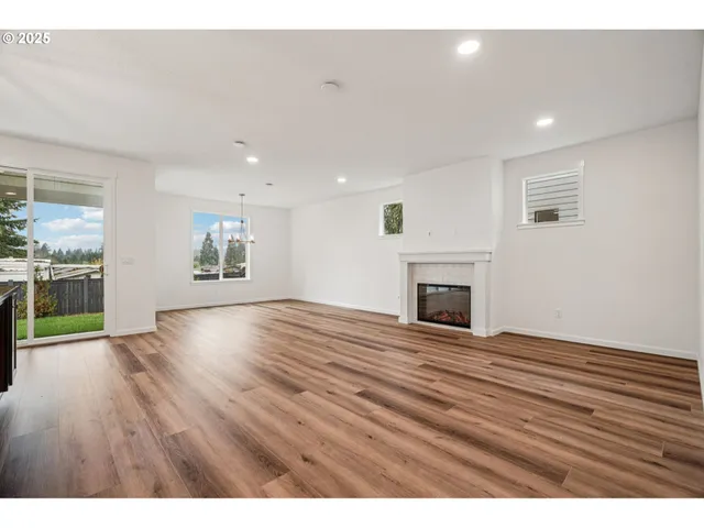 a view of empty room with wooden floor and fireplace
