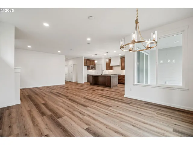 a view of a kitchen with a dishwasher kitchen island wooden floor and chandelier