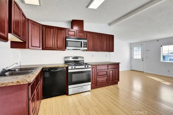 a kitchen with stainless steel appliances granite countertop a stove a sink and a microwave