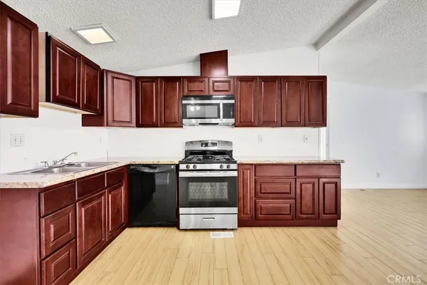 a kitchen with stainless steel appliances granite countertop a stove a sink dishwasher and a refrigerator