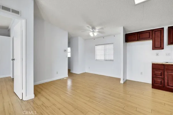 an empty room with wooden floor and ceiling fan