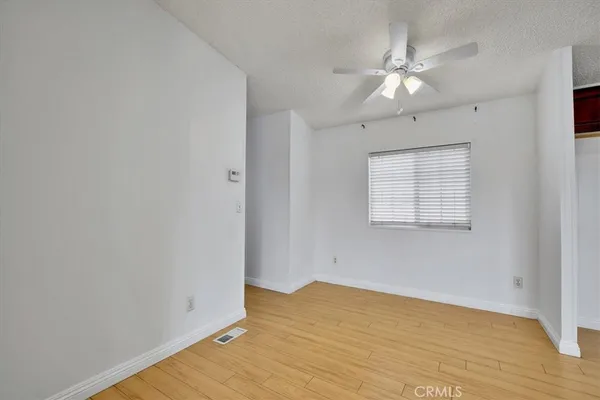 an empty room with wooden floor and fan