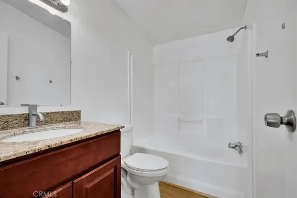a bathroom with a granite countertop sink a toilet and shower