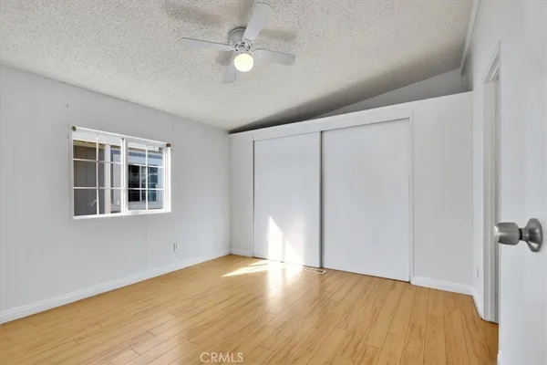 a view of empty room with wooden floor and fan