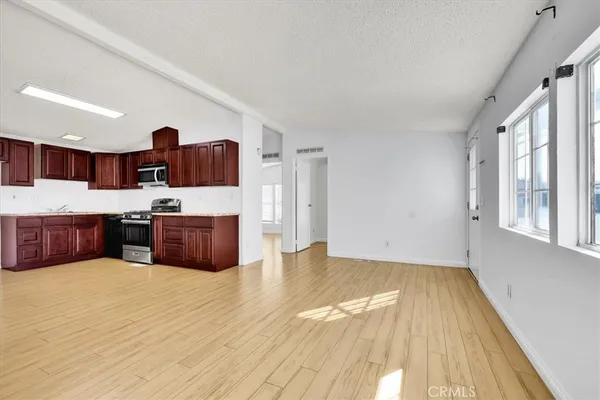 a large kitchen with stainless steel appliances wooden floors and large window
