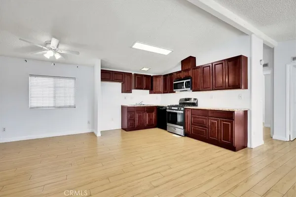 a kitchen with stainless steel appliances granite countertop a stove a sink dishwasher and a refrigerator with wooden floor