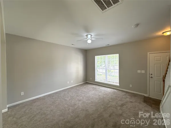 an empty room with windows and fan