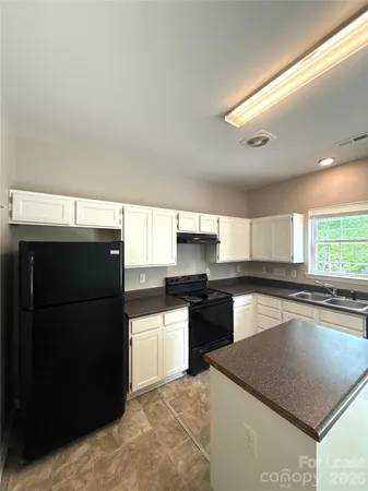 a kitchen with stainless steel appliances granite countertop a refrigerator a sink dishwasher a stove and white cabinets with wooden floor