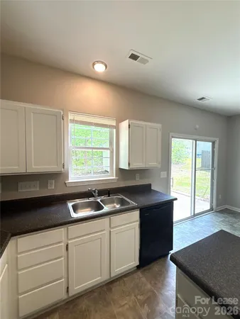 a kitchen with granite countertop a sink white cabinets and window