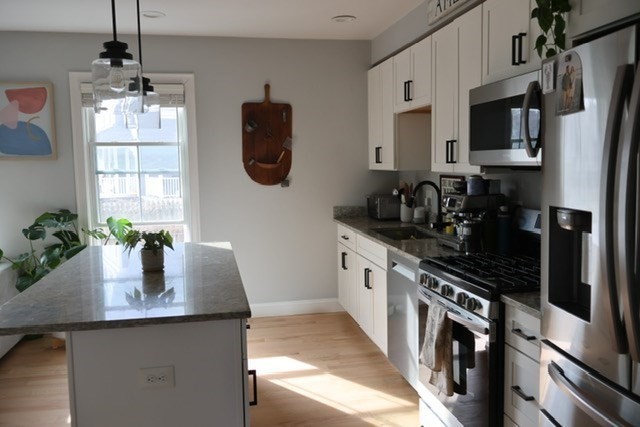 4 Cushing Street, Unit A Amesbury, MA 01913 - Photo 7 of 19 a kitchen with stainless steel appliances granite countertop a sink a stove and a wooden floors