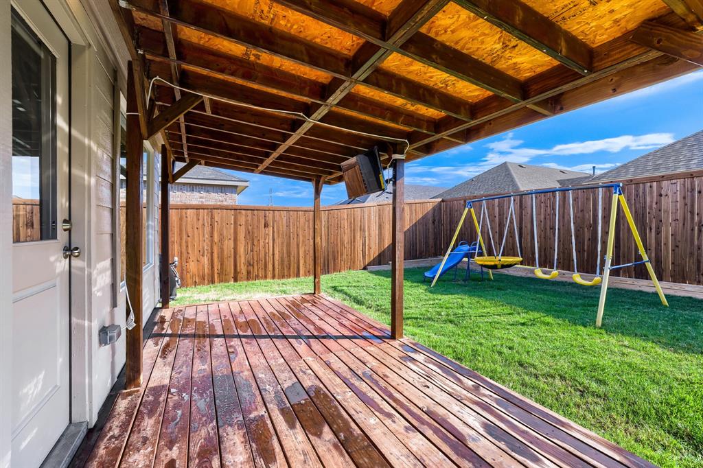 1619 Grassy Pond Road Forney, TX 75126 - Photo 27 of 28 Covered wood deck with exposed wood rafters, overlooking a fenced yard with a manicured lawn