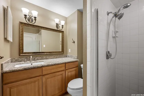a bathroom with a granite countertop sink toilet a mirror a vanity and shower