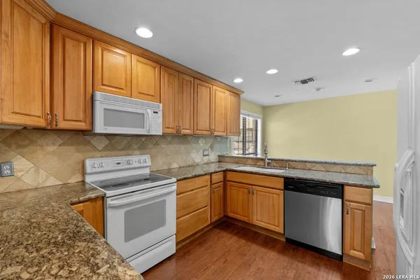 a kitchen with stainless steel appliances granite countertop wooden cabinets and a stove top oven