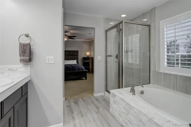 a spacious bathroom with a granite countertop tub sink a mirror and shower