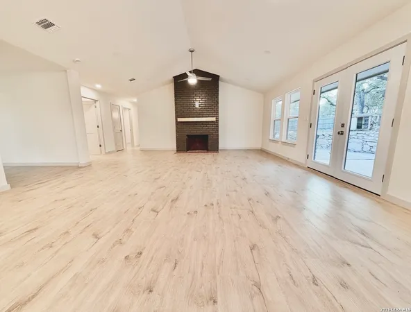a view of an empty room with a window and wooden floor