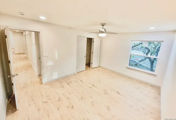 a view of a hallway with wooden floor and chandelier fan