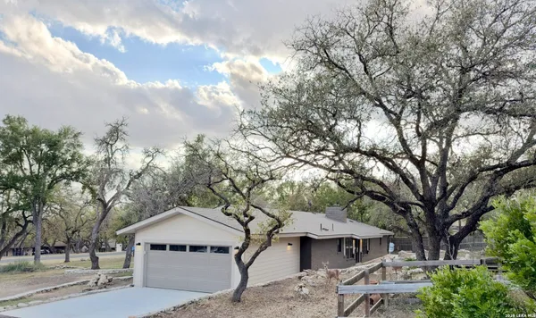 a view of a house with a yard and large tree
