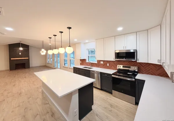 a kitchen with stainless steel appliances kitchen island granite countertop a stove a sink and a microwave