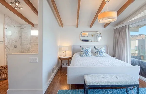 a bedroom with a bed and a lamp on dresser with a large window