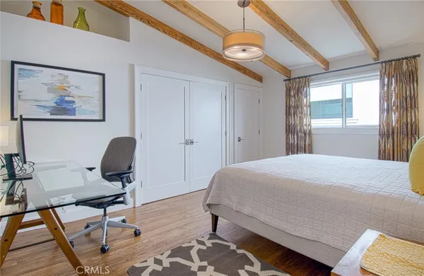 a bedroom with a bed a desk and chair with wooden floor