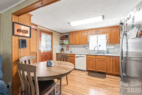 a kitchen with stainless steel appliances granite countertop a sink a stove a refrigerator with a dining table and chairs