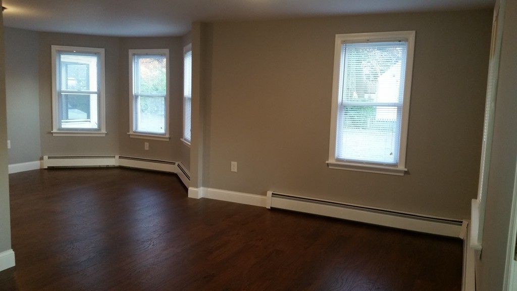 49 Drexel Street Springfield, MA 01104 - Photo 23 of 30 an empty room with wooden floor and windows with curtains