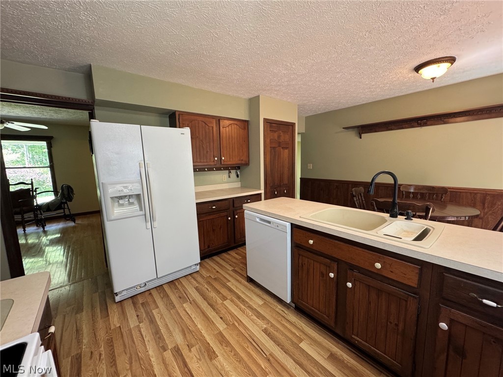 8201 Orchard Road Painesville, OH 44077 - Photo 10 of 45 Kitchen featuring wood-finish laminate flooring, wood cabinetry with white hardware, light countertops, and a double basin sink with a black gooseneck faucet