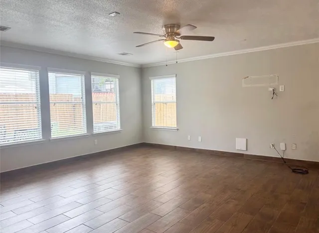 an empty room with wooden floor and windows