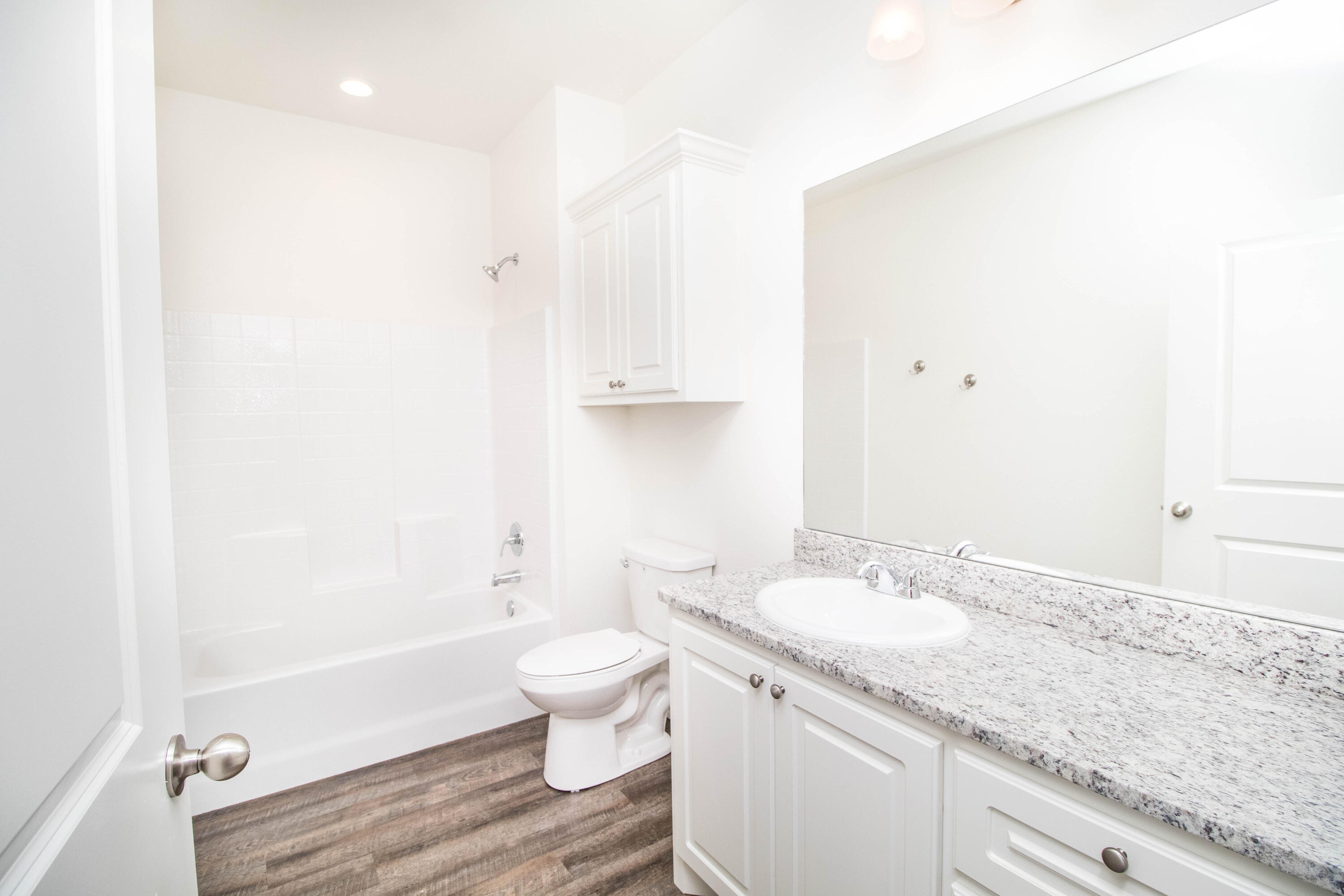 6914 21st Street Lubbock, TX 79407 - Photo 11 of 36 a bathroom with a granite countertop sink a toilet and bathtub