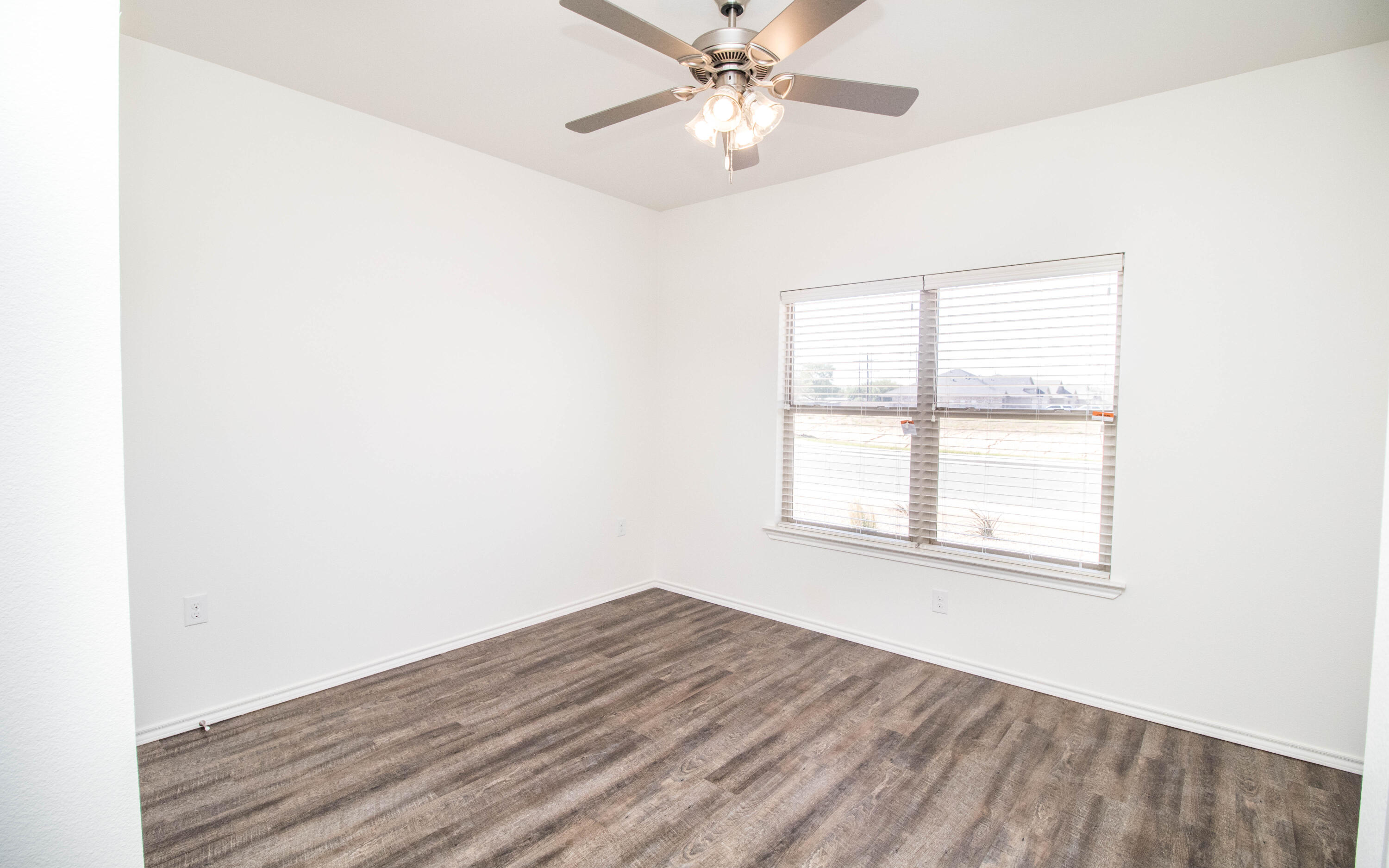 6914 21st Street Lubbock, TX 79407 - Photo 30 of 36 an empty room with wooden floor fan and windows
