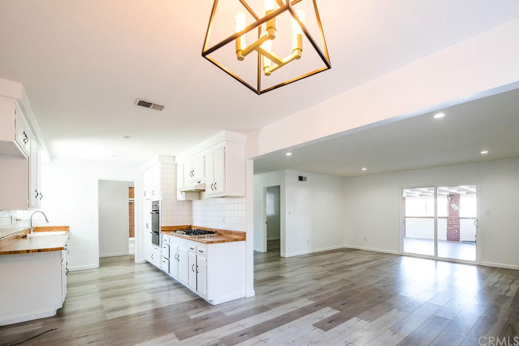 a large kitchen with a center island wooden floor and stainless steel appliances