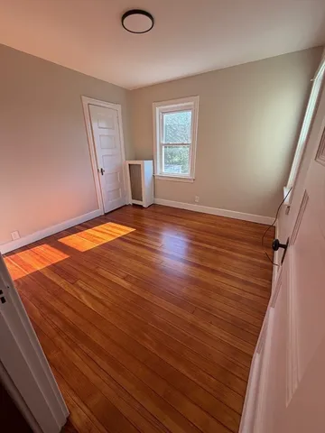 a view of empty room with window and wooden floor